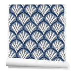 A hanging roll of wallpaper with a repeating Moroccan-inspired scallop pattern in navy and white on a blue background.