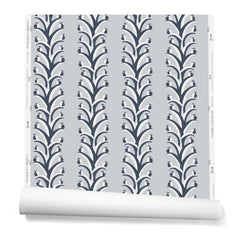 A hanging roll of wallpaper with repeating horizontal stripes of white and charcoal branches and fruit. Background is light gray.