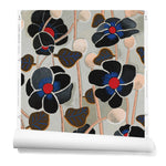 A hanging roll of wallpaper with a large-scale repeating poppy motif in shades of black, red, blue and tan on a light blue background.