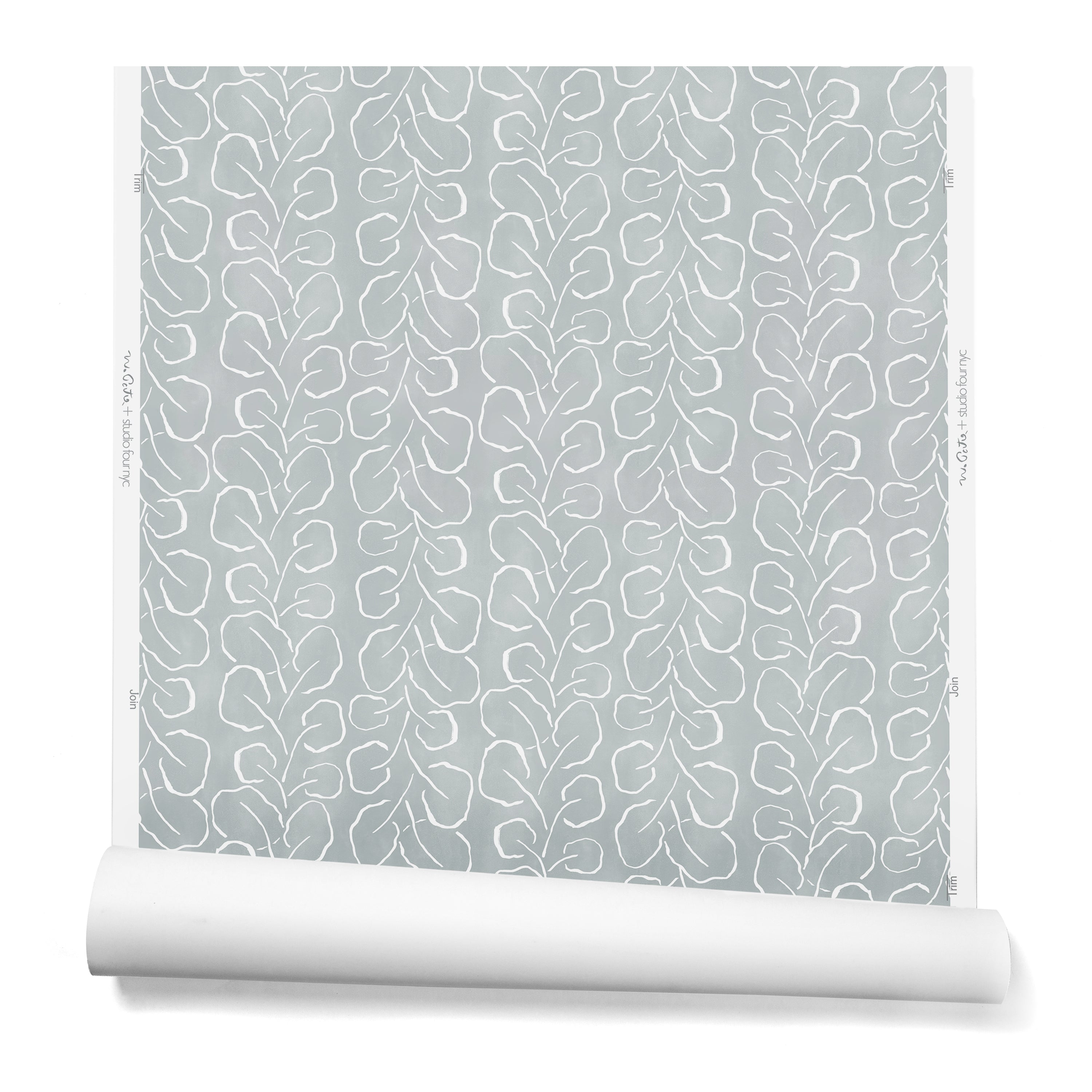 A hanging roll of wallpaper with a large-scale repeating leaf print in white on a blue-gray watercolor background.
