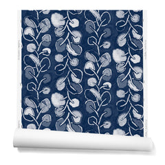 A hanging roll of wallpaper with repeating rows of colorful leaf prints in shades of blue and white on a navy background.