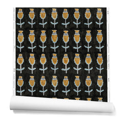 A hanging roll of wallpaper with repeating rows of a watercolor flowers in gray, mustard and light blue on a black background.