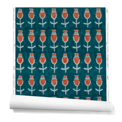 A hanging roll of wallpaper with repeating rows of a watercolor flowers in red, gray and blue on a turquoise background.