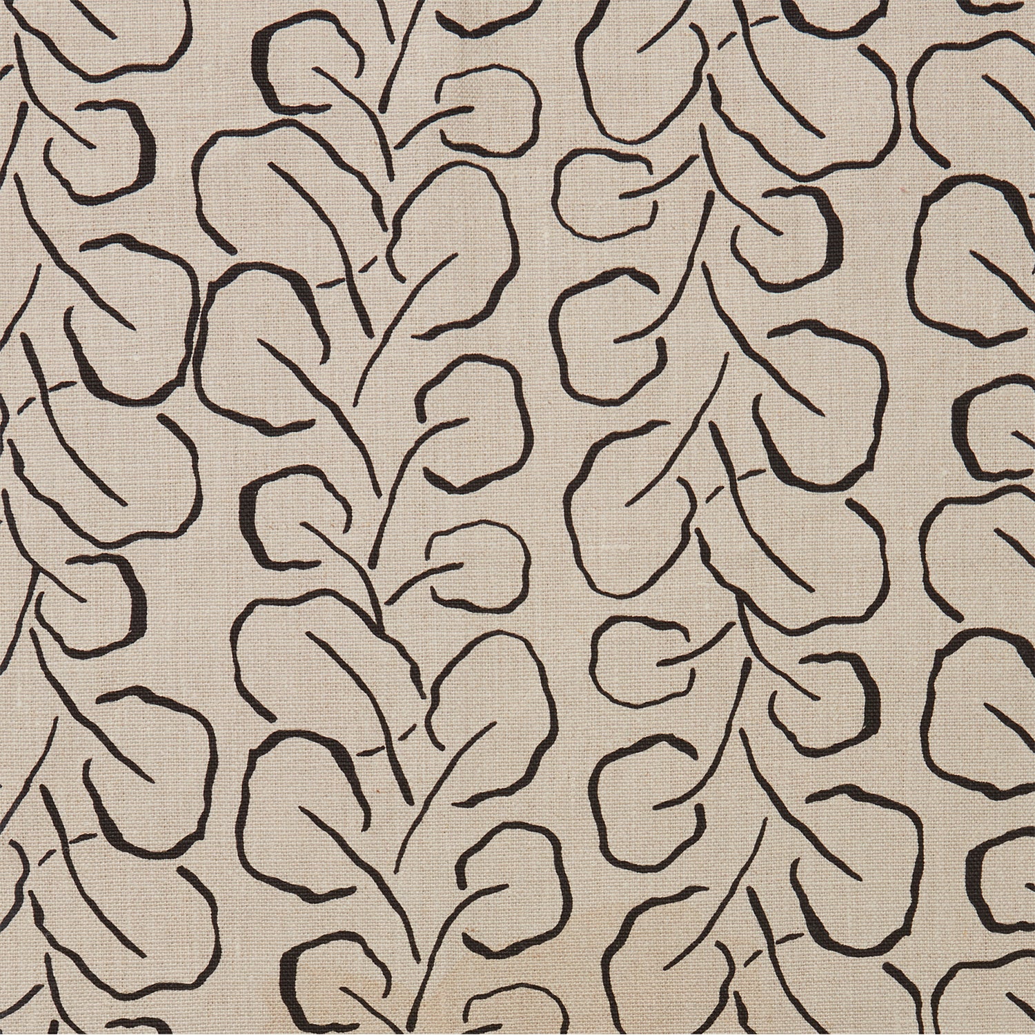 Woven fabric swatch with a large-scale repeating leaf print in black on a tan background.